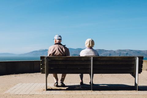 Old couple sit by the beach on a bench