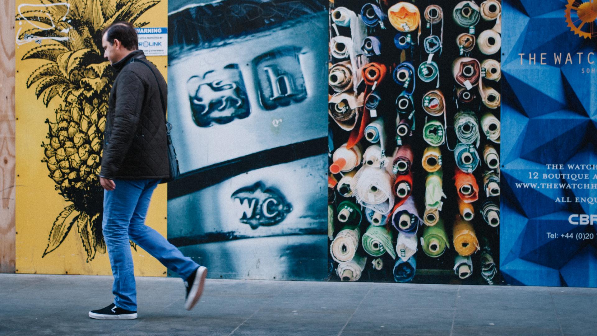 Person walking against a vibrant wall covered in graphic imagery