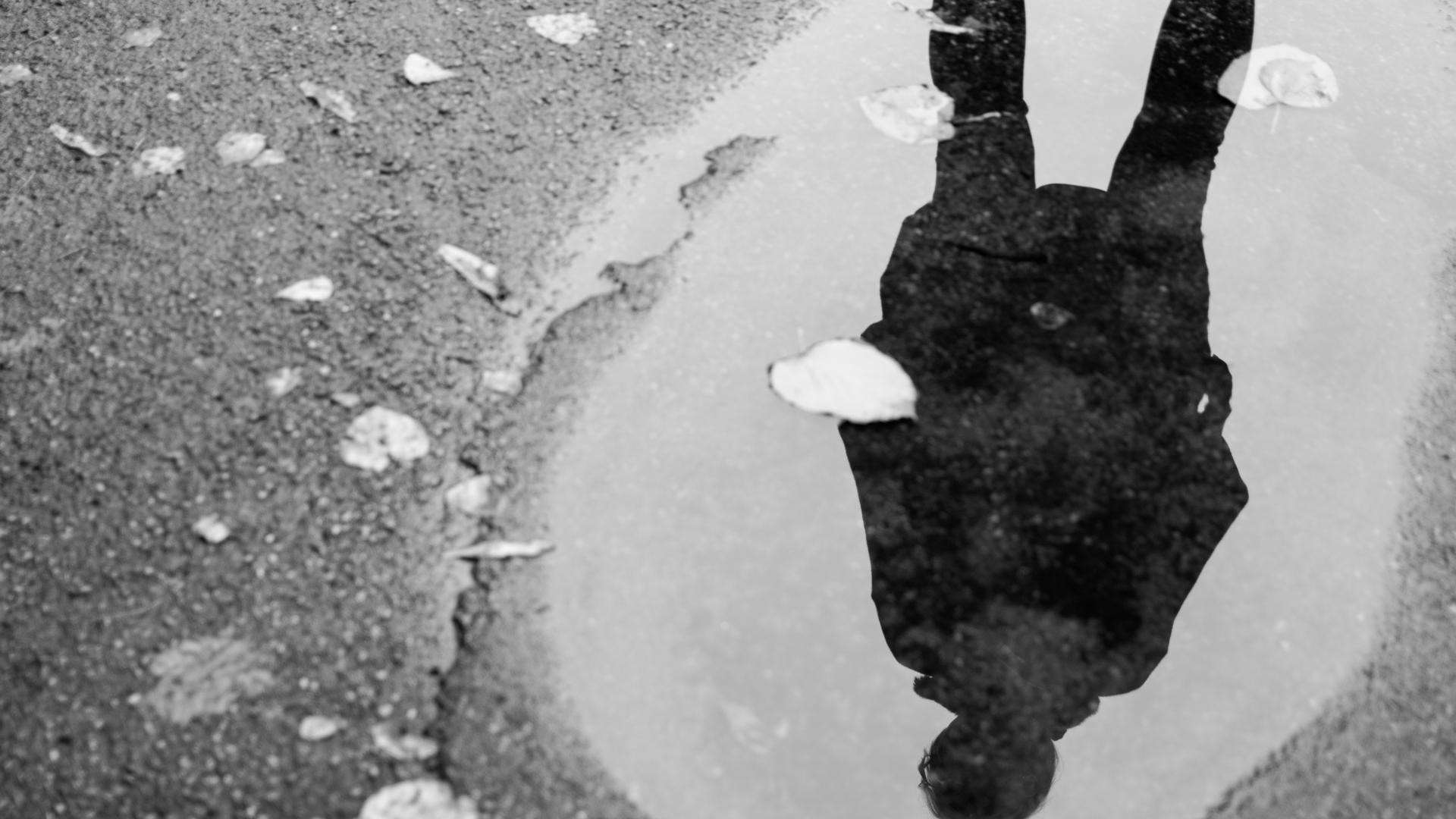 A man reflected in a puddle