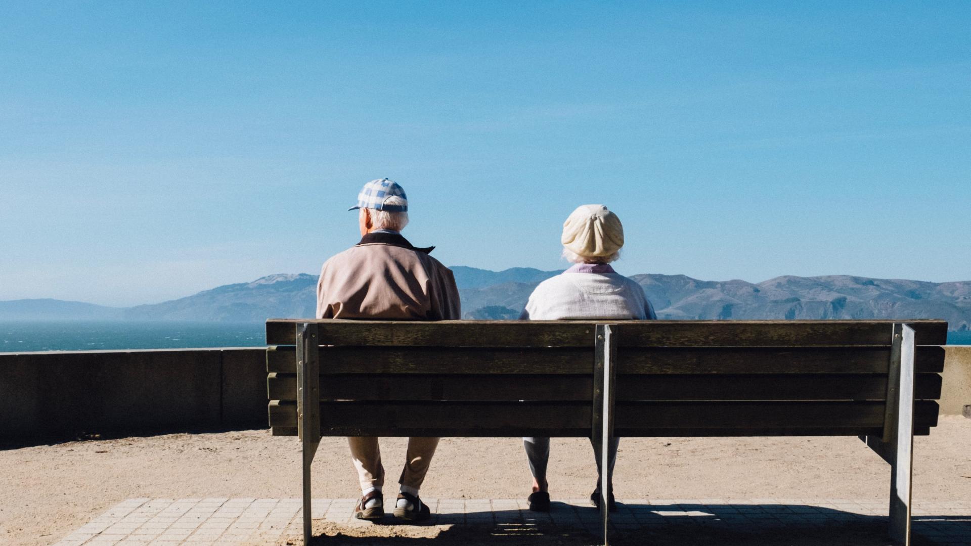 Old couple sit by the beach on a bench